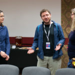 Grupa trzech osób podczas rozmowy. Mężczyzna rozkłada ręce.