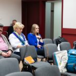 Grupa osób siedzi i słucha referatów.