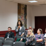 Kobieta stoi i mówi do mikrofonu w trakcie dyskusji po referatach.