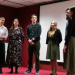 Grupa kobiet i mężczyzn prezentuje śpiew podczas konferencji.