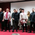 Grupa kobiet i mężczyzn prezentuje śpiew podczas konferencji.