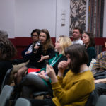 Uczestnicy konferencji podczas dyskusji. Jedna z kobiet mówi do mikrofonu.