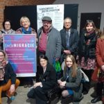 Grupa kobiet i mężyczyzn na Targowisku Instrumentów. Dwie kobiety trzymają duży oprawiony plakat konferencji.